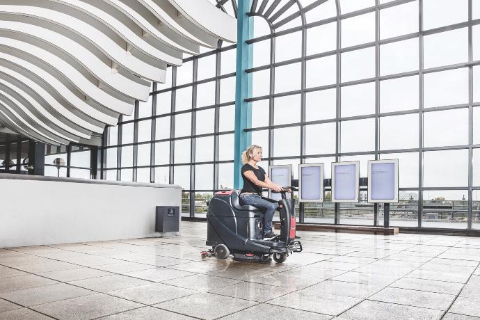 Ride-on scrubber cleaning the floor inside a public community building